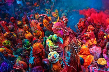 A large crowd revels, each covered from head to toe in colourful powder