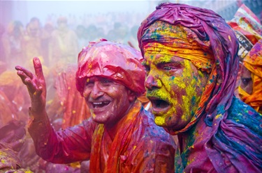 Two middle-aged men appear exhausted and smiling. They are soaked in coloured water.